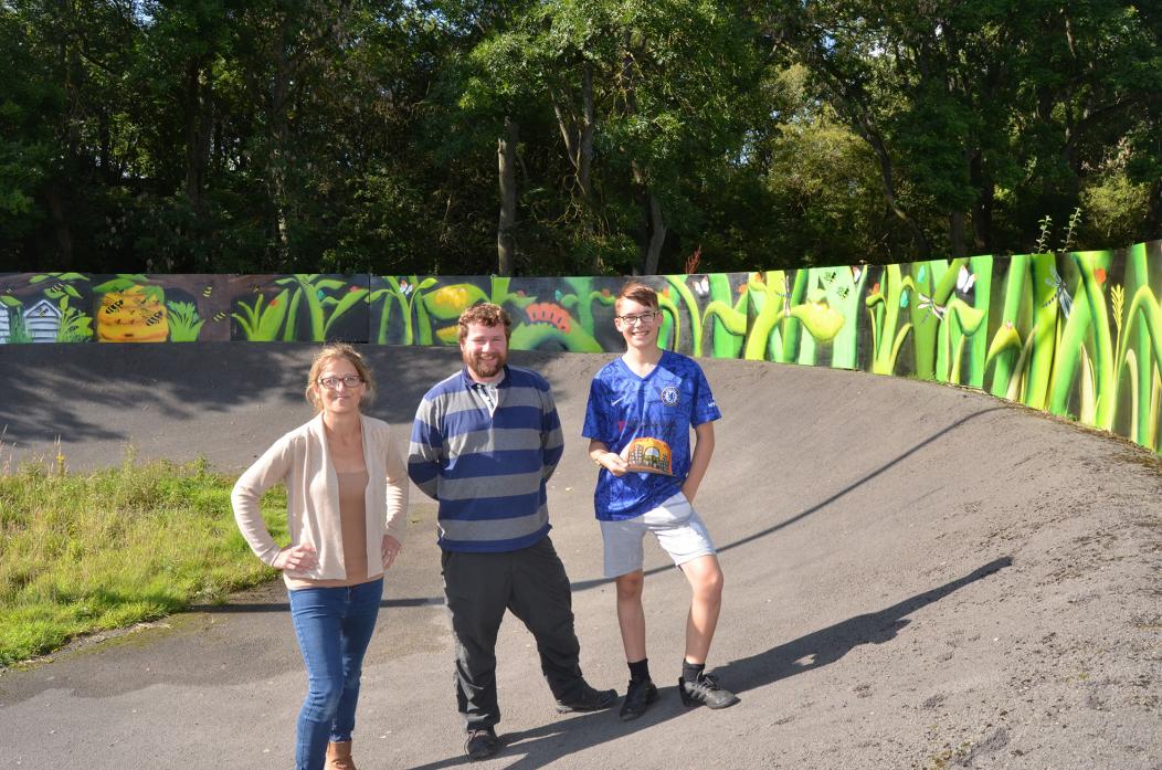 ART PROJECT: Sam Tranter, from the AONB, with Nat Wilkins, art education co-ordinator and one of the youngsters, Tommy White, who helped design and spray paint the new mural