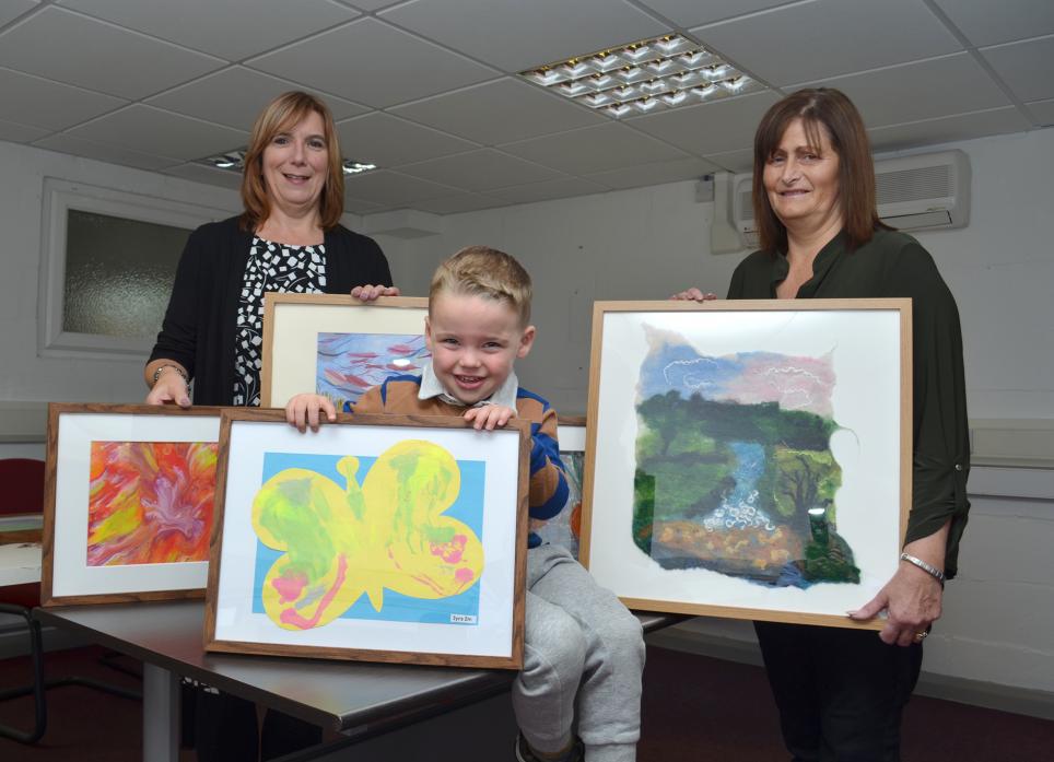 FESTIVE FUNDRAISER: Little Freddie Gregory, 3, shows of the picture he has painted for Graham’s Gallery. Bowes Christmas Lights treasurer Lynn Todhunter and secretary Gill Close show off some of the other work submitted to raise funds for the illumination