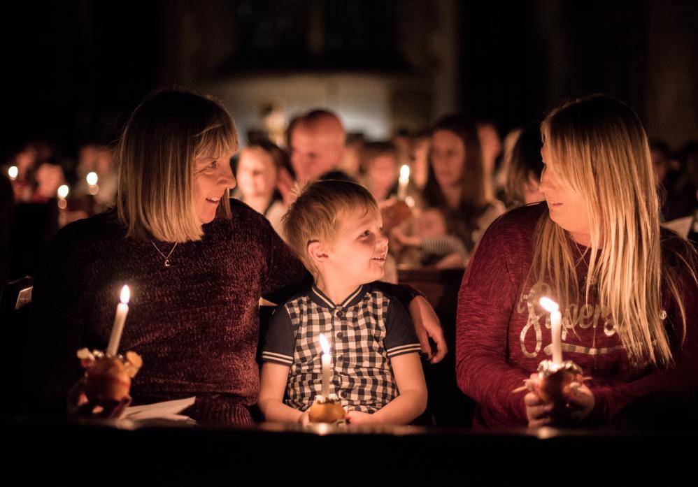 LIT UP: Lizzie and Chloe Allinson with little Logan and their Christingles at last year’s service