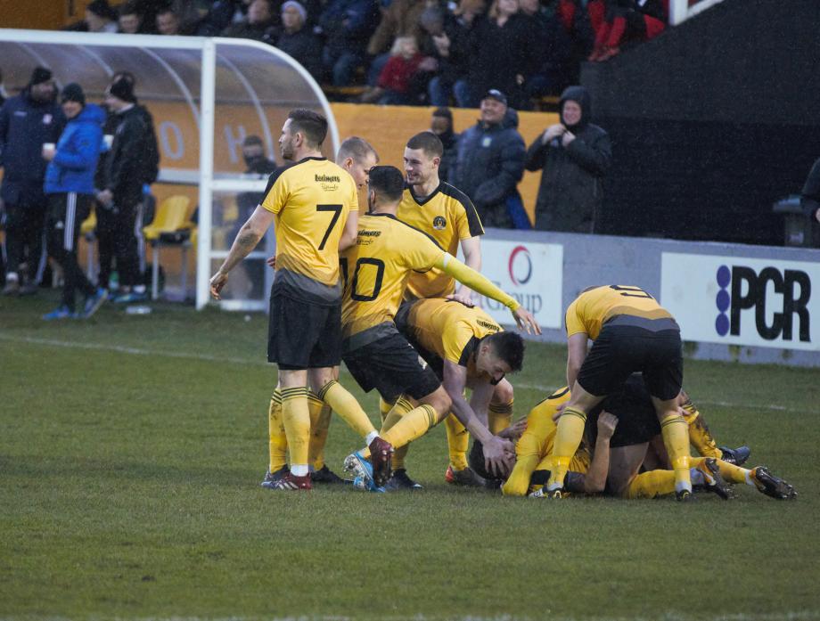 WINNER: West skipper Lewis Dodds is smothered by his team mates after scoring the only goal in Saturday’s FA Vase cup tie Pic: Andy Mitchell