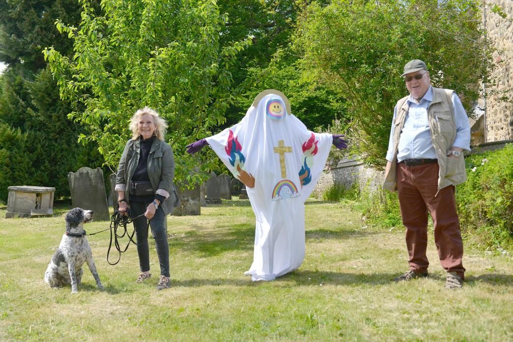 QUITE A SIGHT: Gerry Appleyard and her dog Reg, along with Angling Trust bailiff Arthur Raper view the vicar scarecrow at St Mary’s Church