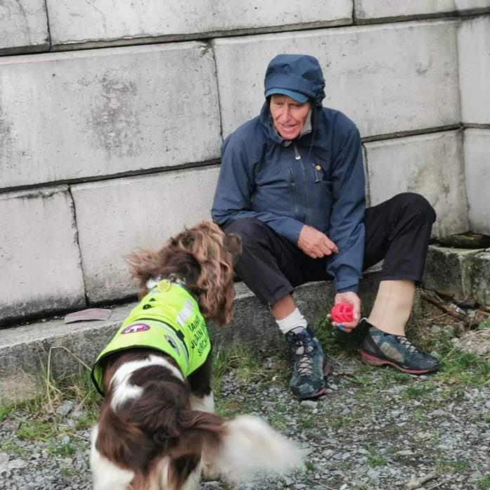 FOUND YOU: Alan Hinkes is found by a rescue search dog and its handler during a training exercise high up in the moors. Inset, the ‘dogsbody’ badge the mountaineer wears during training exercises