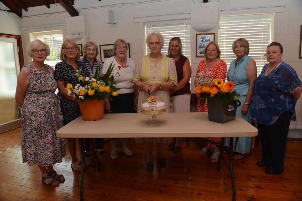 ANNIVERSARY CAKE: Chairwoman Marion Lewis, flanked by treasurer Christine Duke and secretary Christine Richardson prepares to cut the anniversary cake while members of Dalton Flower Club look on