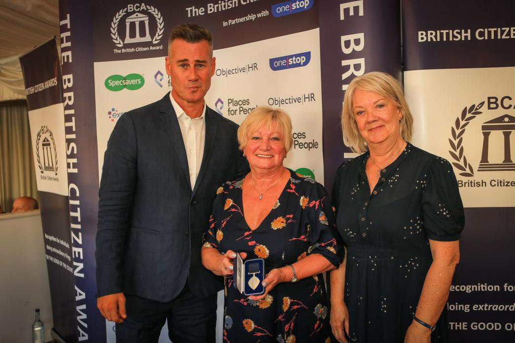 WELL DESERVED: Charity fundraiser and volunteer Pam Ashmore received her British Citizen’s award from by TV personality Tim Vincent and Specsavers founder Dame Mary Perkins